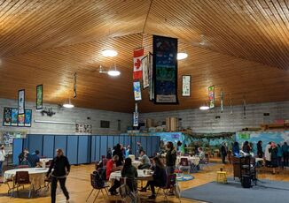 The vaulted interior of the Urban Indigenous Education center.  Flags of Canada and Indigenous nations hang from the ceiling.